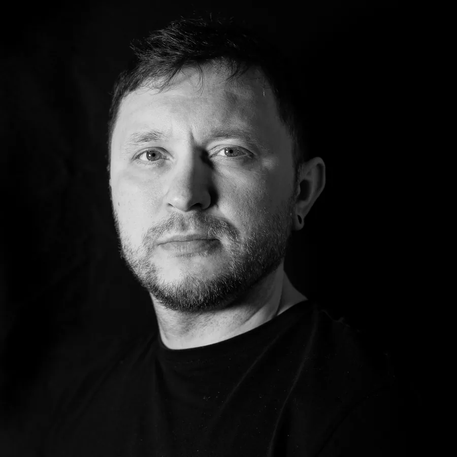 Alex, blackwork specialist, photographed against black in the studio in a plain black tee.