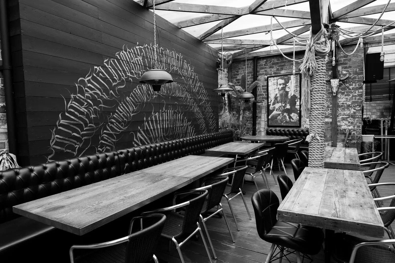 The lounge: a long communal table with bench and stool seating, run under a pleated fan mural and pendant lighting.