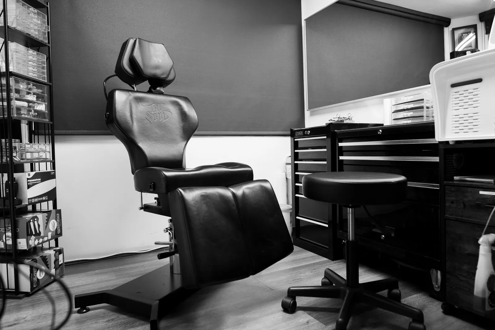 The piercing room: an upright leather chair beside a stainless steel trolley, jewellery displayed on the wall rack alongside.