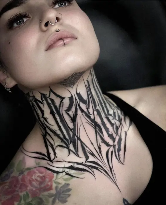 A blackwork neck piece in a sharp brushed style, spikes fanning from the throat to the collarbone.