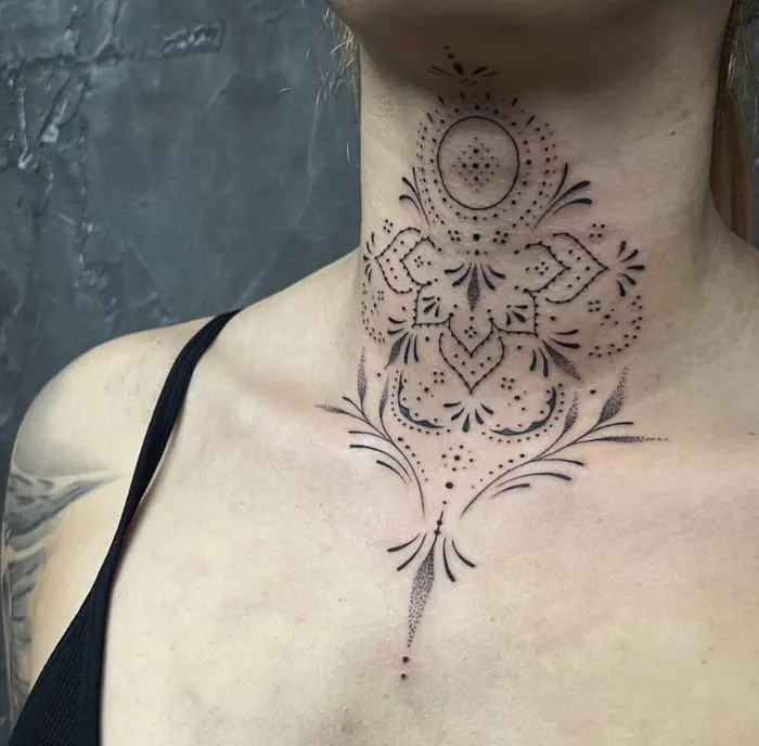 A blackwork ornamental piece across the neck and upper chest, symmetrical dotwork dropping to a fine point.