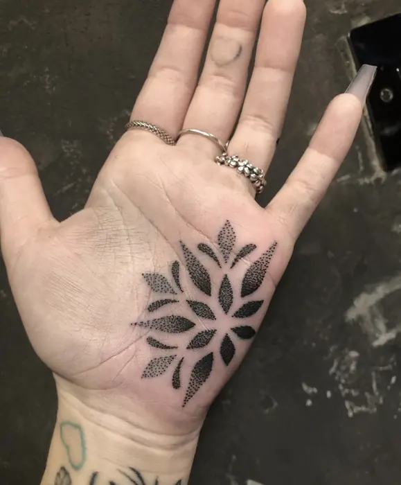 A blackwork geometric mandala in the palm of the hand, worked in fine dotwork.