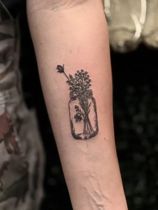 A small fine line jar of wildflowers on the inner forearm.