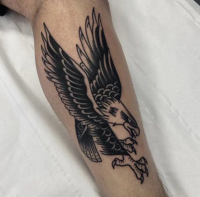 A traditional eagle in flight on the forearm, worked in solid black with heavy line weight.