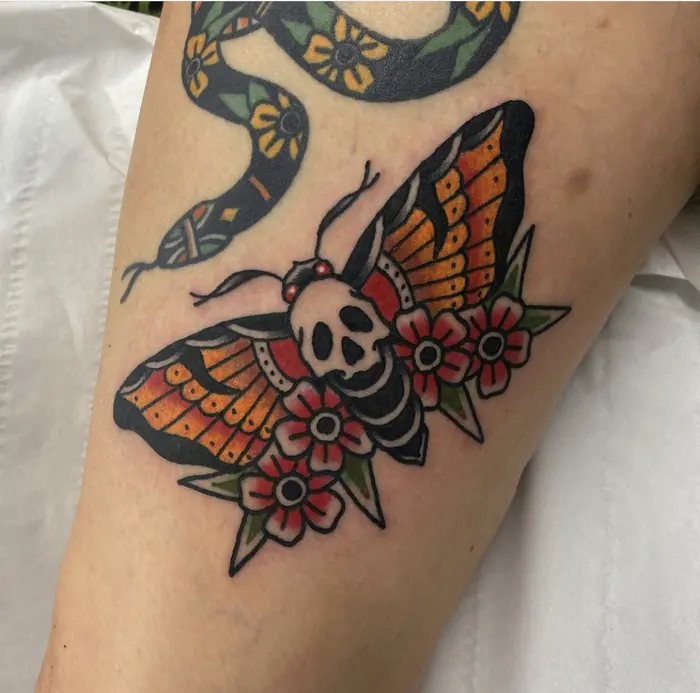 A neo-traditional death's-head moth on the upper arm with a snake curling behind it.