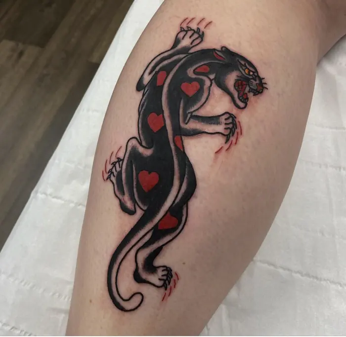 A neo-traditional crawling panther on the calf, heavy black with red claw marks.
