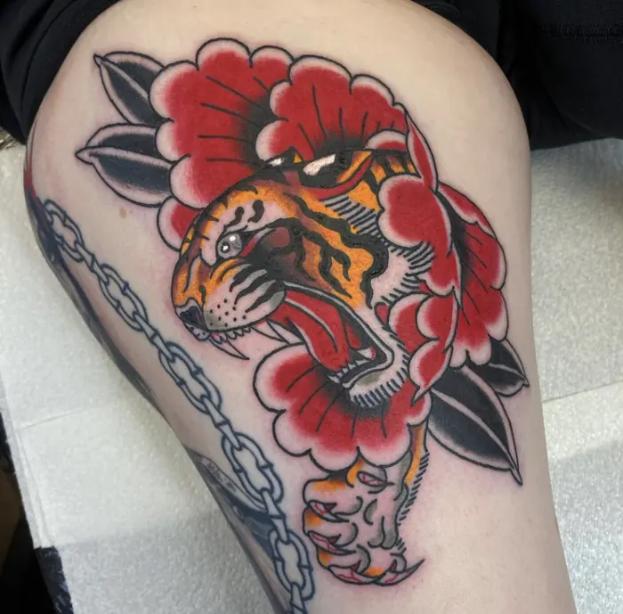 A neo-traditional panther and rose on the thigh, a broken chain worked in beneath.