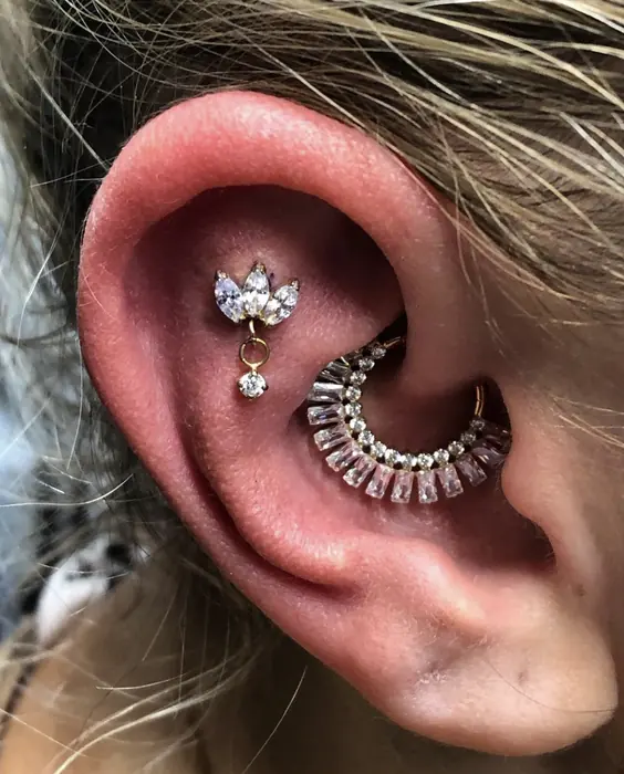 A daith clicker with a graduated gem cluster, sitting inside the fold of the ear.