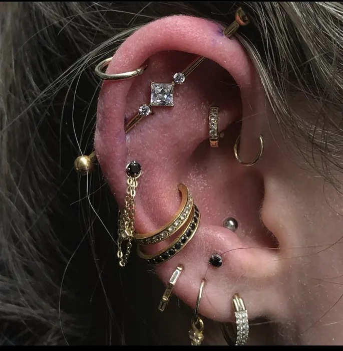 A helix and flat stack in mixed gold and black, five pieces curated around the upper ear.