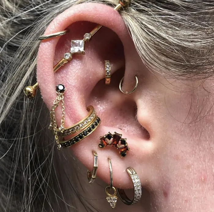 A full ear stack in gold: rings, clickers and studs curated up the helix and through the lobe.