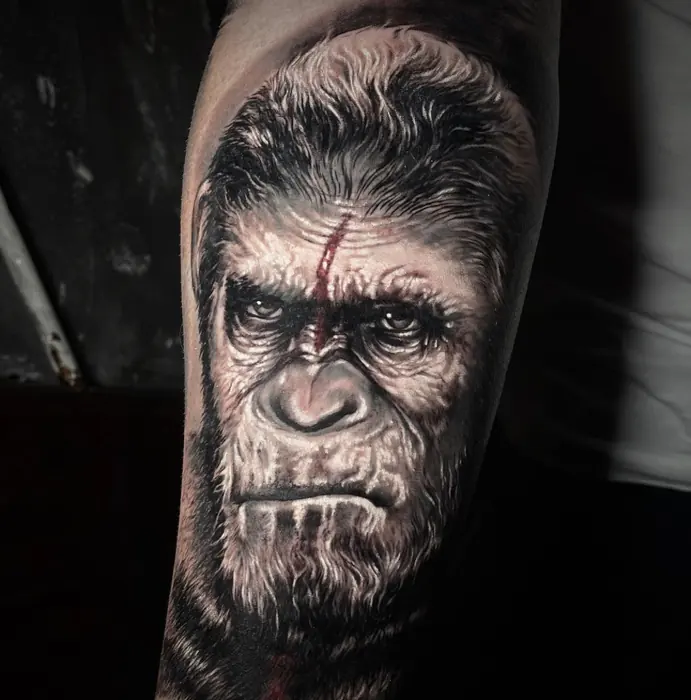 A black and grey realism gorilla portrait on the upper arm, the eyes and brow carrying the whole piece.